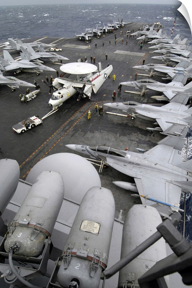 Sailors move an E2C Hawkeye down the crowded flight deck aboard USS Kitty Hawk