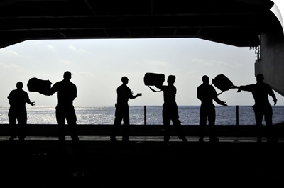 Sailors pass supplies to each other in the hangar bay of USS Ronald Reagan