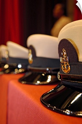 Several chief petty officers combination covers lined up on a table