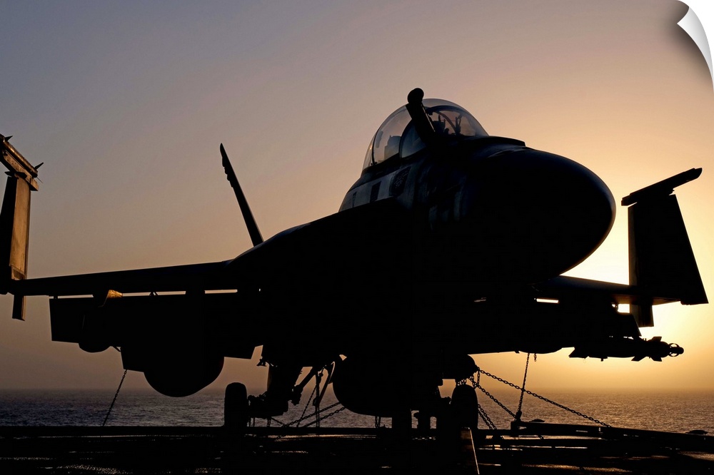 Silhouette of a US Navy F/A-18E Super Hornet parked on the flight deck of aircraft carrier USS Nimitz off the coast of Pak...