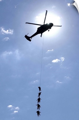 Soldiers and Airmen hang 100 feet above the ground from a UH-60 Blackhawk