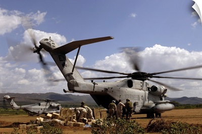 Soldiers And Sailors Help Pile Boxes Of Food And Water Off A CH-53E Helicopter