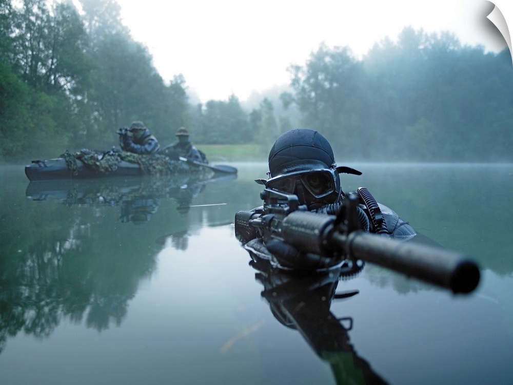 Landscape photograph of a special operations forces combat diver just above foggy water,  armed with an assault rifle.  A ...