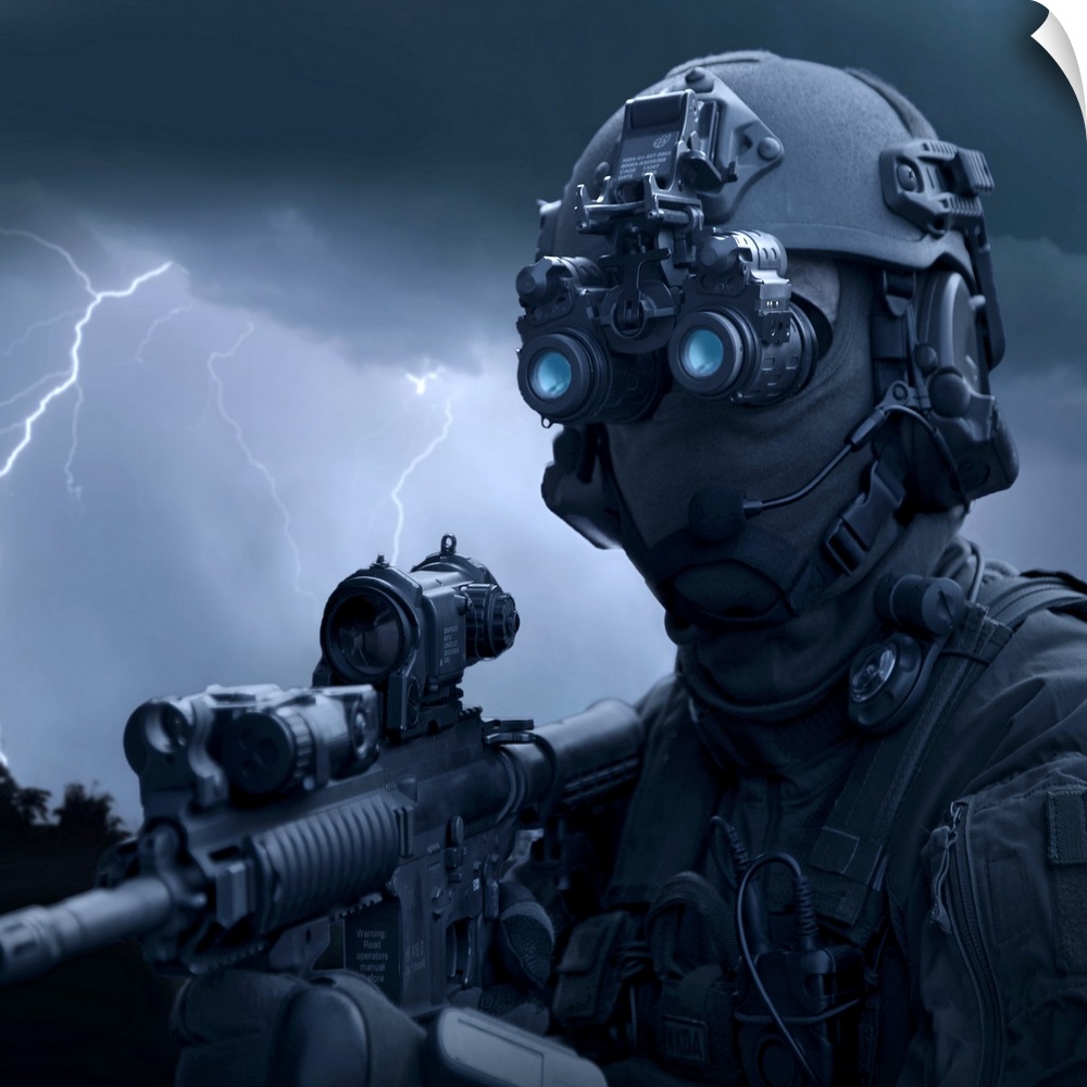 Large horizontal photograph of a special operations soldier holding an HK416 assault rifle and wearing night vision goggle...