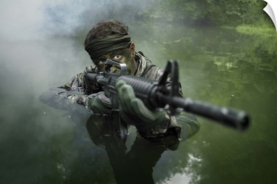 Special operations forces soldier transits the water armed with an assault rifle