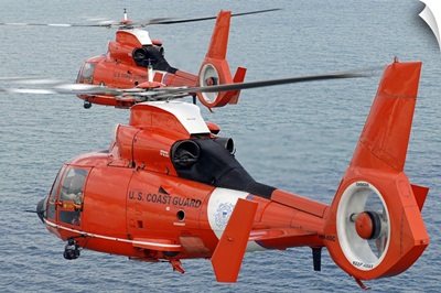 Two Coast Guard HH 65C Dolphin helicopters fly in formation over the Atlantic Ocean