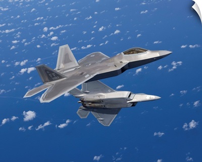Two F-22 Raptors maneuver while flying a training mission over Japan