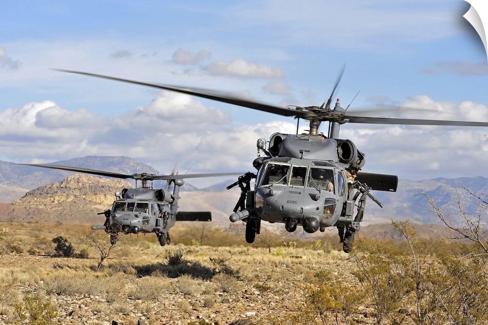 A couple of military copters hovering a few feet off the ground in a desert during a training exercise.