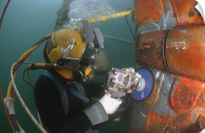 US Navy Diver Files Down A Repair Patch On The Submerged Bow Of The USS Ogden
