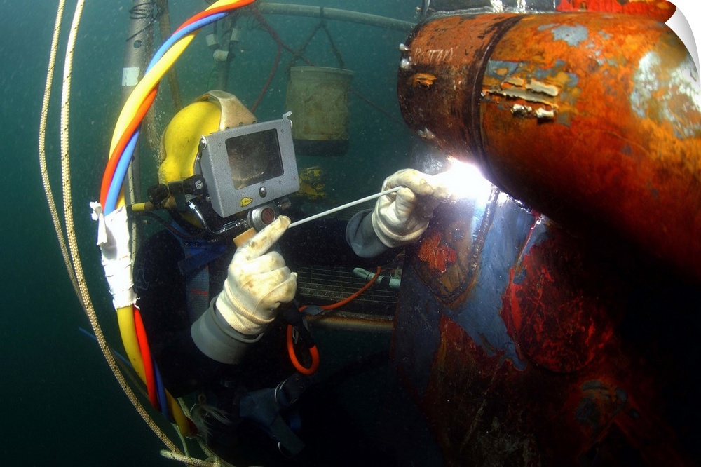 U.S. Navy Diver welds a repair patch on the submerged bow of the USS Ogden.