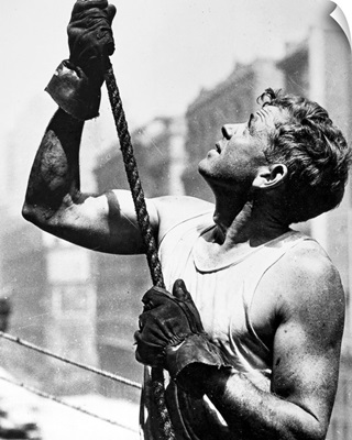 A construction worker gripping a rope at work on the Empire State Building, 1931