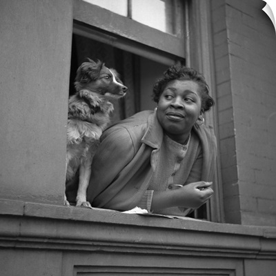 A woman and her dog in the window of their apartment in Harlem, 1943