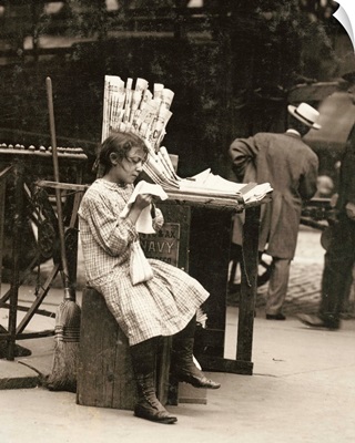 A young newsgirl seated on a crate while tending to the newspaper stand Manhattan, 1910