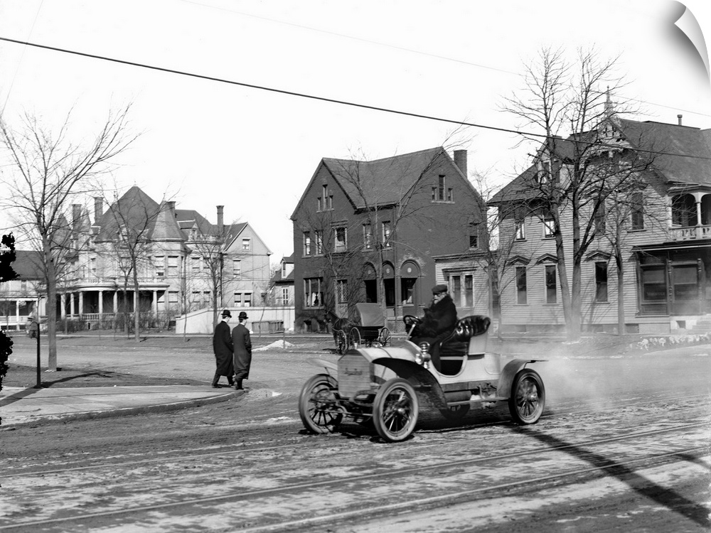 Man driving an automobile through an American town. Photograph, c1905.