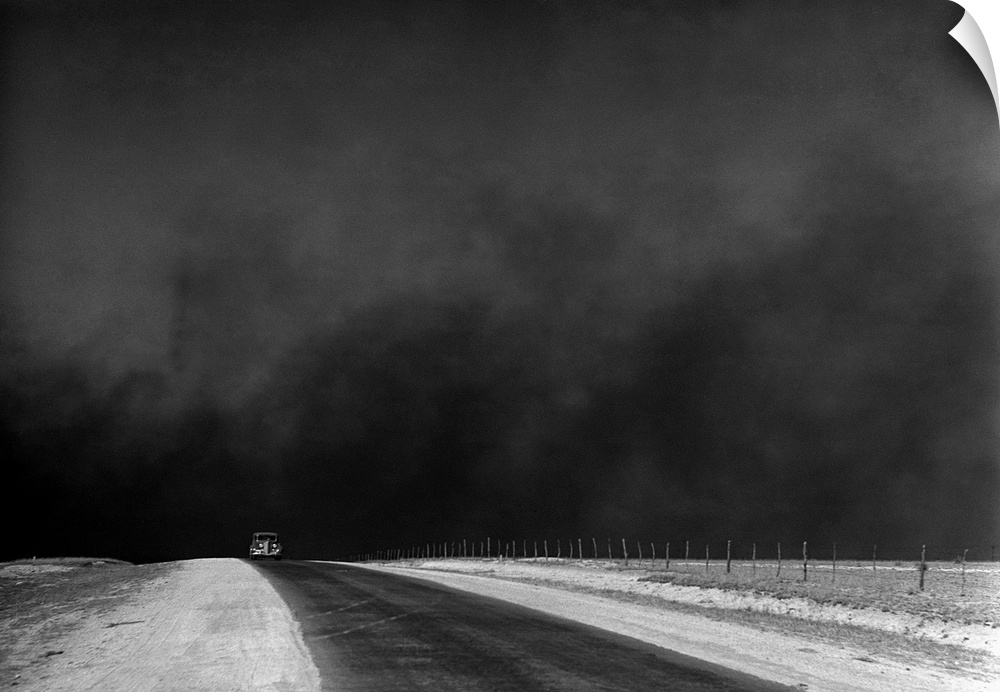 A car on a deserted road with black clouds of dust rising from the horizon, Texas Panhandle, Texas. Photograph by Arthur R...