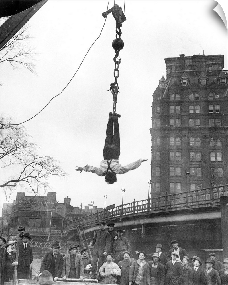 American magician. Houdini at finish of stunt of releasing himself from a straitjacket while suspended in midair; photogra...