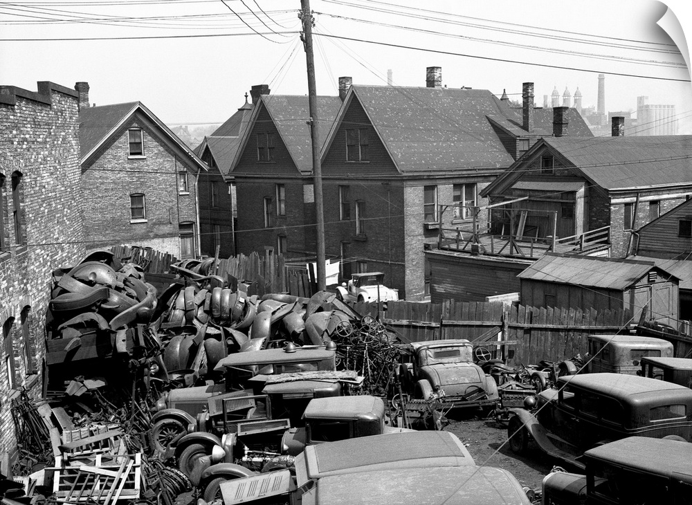 A junkyard with auto parts and scrap metal alongside working class houses, Milwaukee, Wisconsin. Photograph by Carl Mydans...