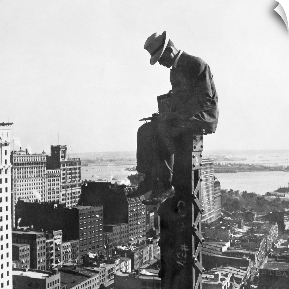 A photographer for H.C. White Co. sitting at the top of a column of a new building in New York City, 250 feet above ground...