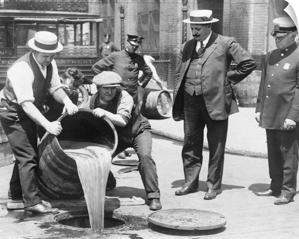 New York City Deputy Police Commissioner, John A. Leach (right), watches agents pour liquor into a sewer after a raid, c1921.
