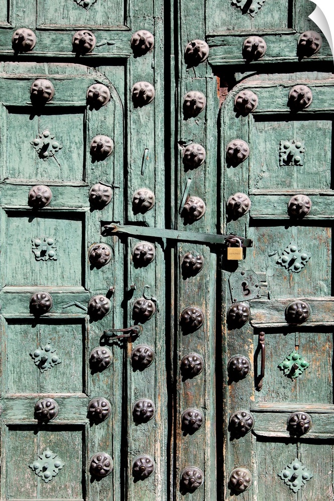 A rustic wooden door painted green with metal embellishments.