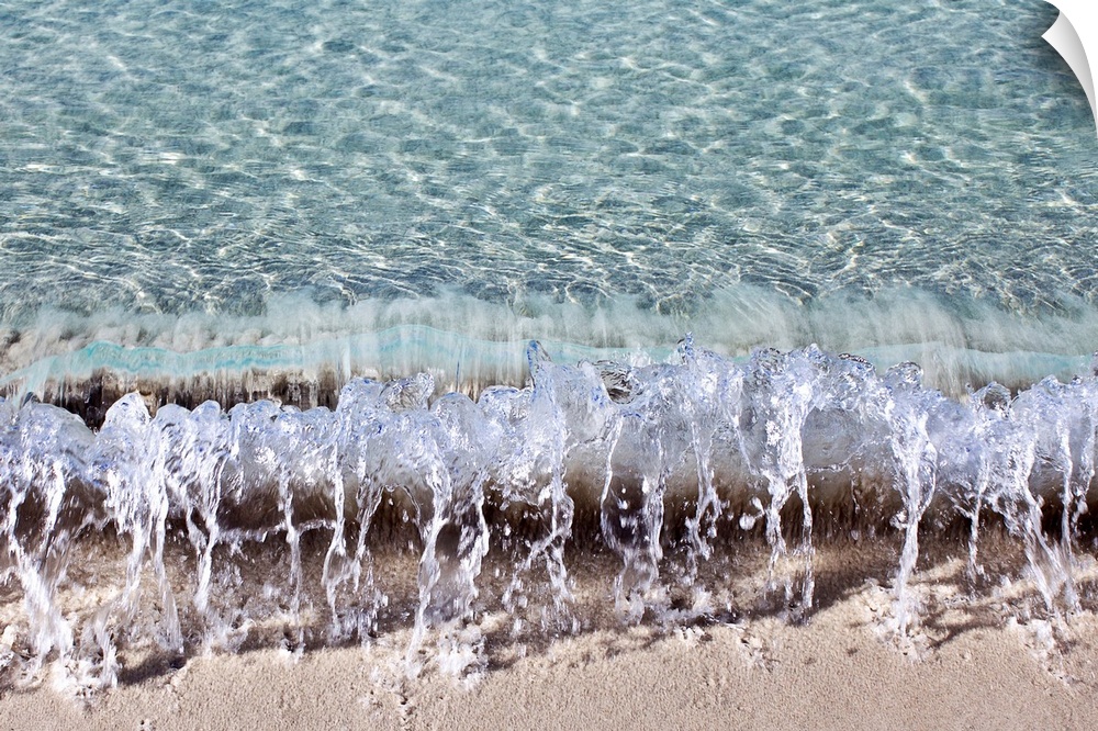 Photograph of a small wave hitting the shore of a beach.