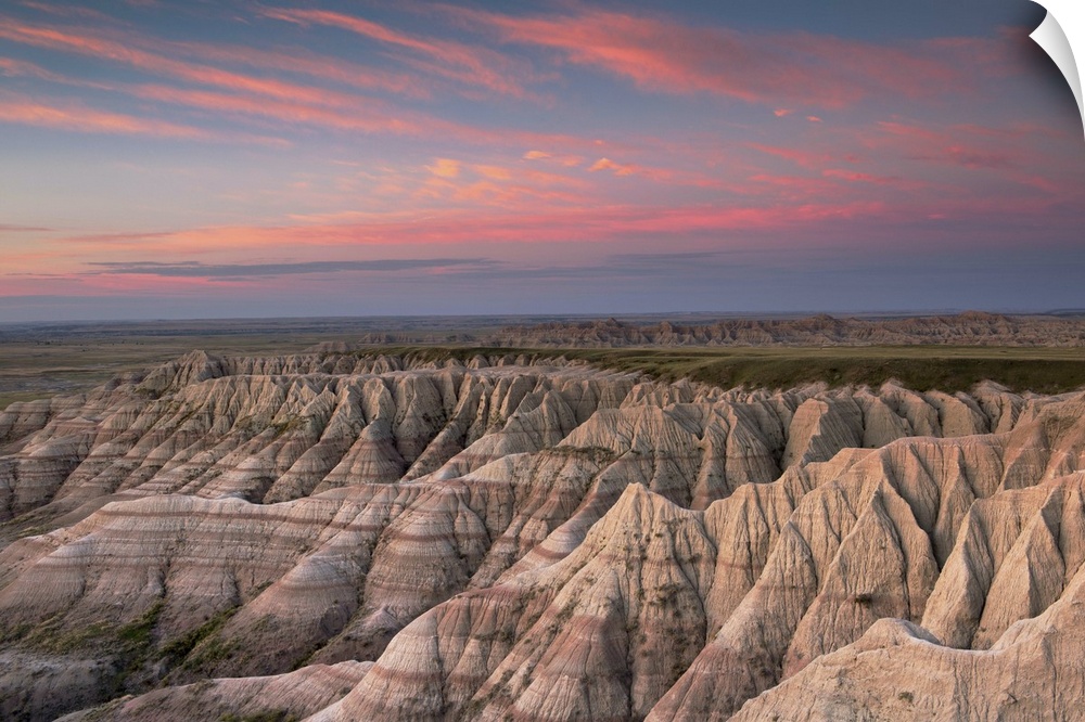 Pink clouds at dawn over the pointed rocky landscape of the South Dakota badlands.