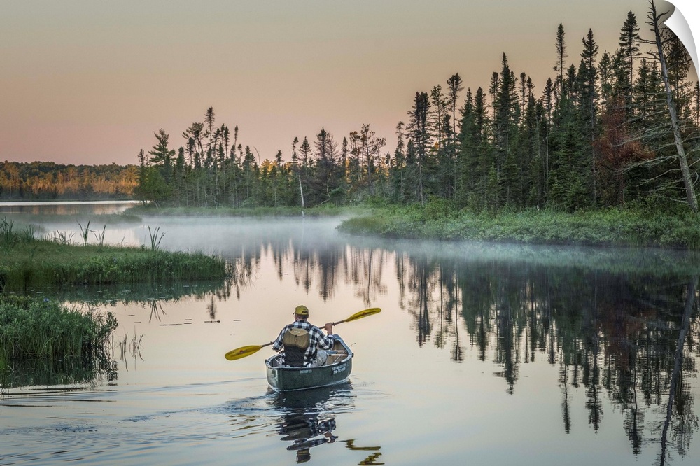 A canoeist paddling in quiet waters in the morning on Madeline Island, Wisconsin.