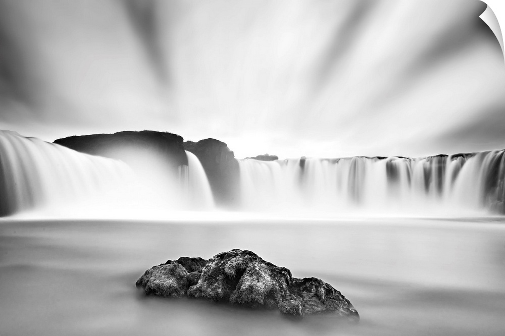 Long exposure image of a waterfall with bright clouds above in Iceland.