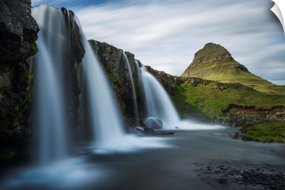 Glacial waterfall in Iceland with a view of Kirkjufell mountain in the distance.