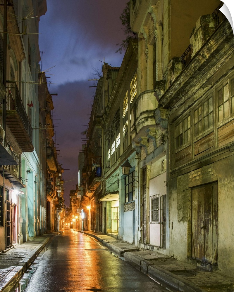 Lights from old buildings reflected on rainy streets in an alley in Havana, Cuba.