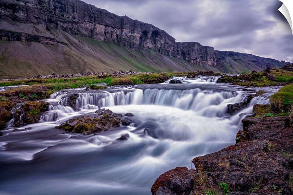 Rushing water in a freezing river under a cloudy sky in Iceland.