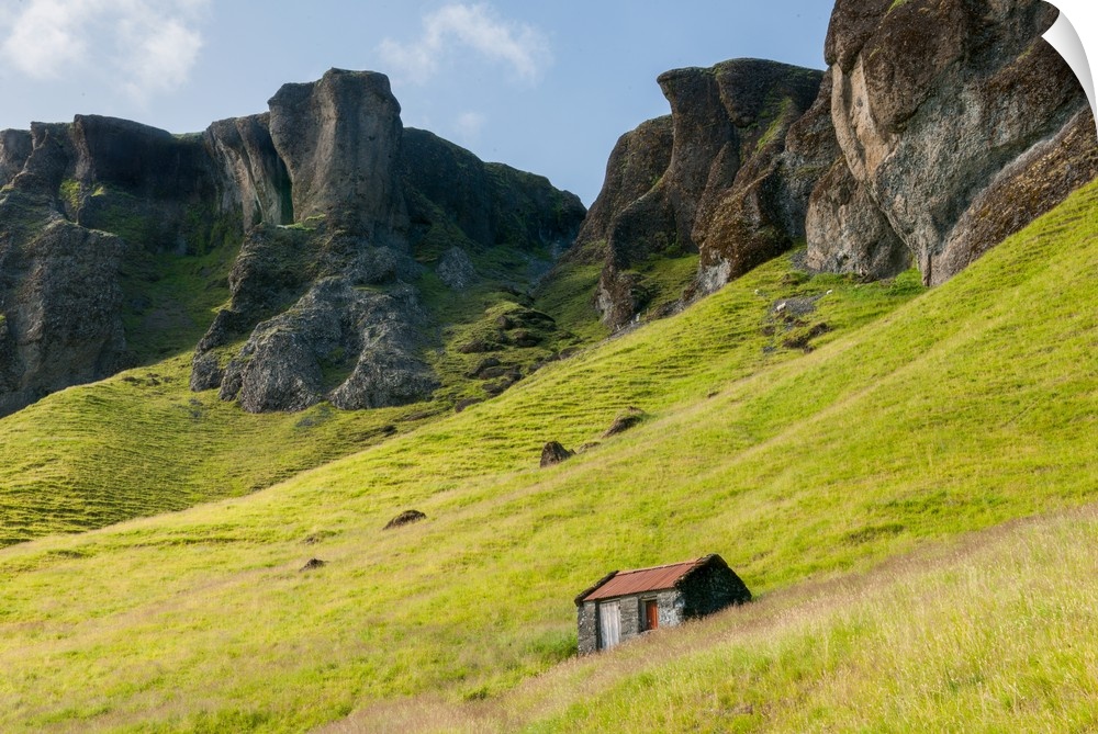 Oddly shaped rock formations emerging from the green landscape with a small house.