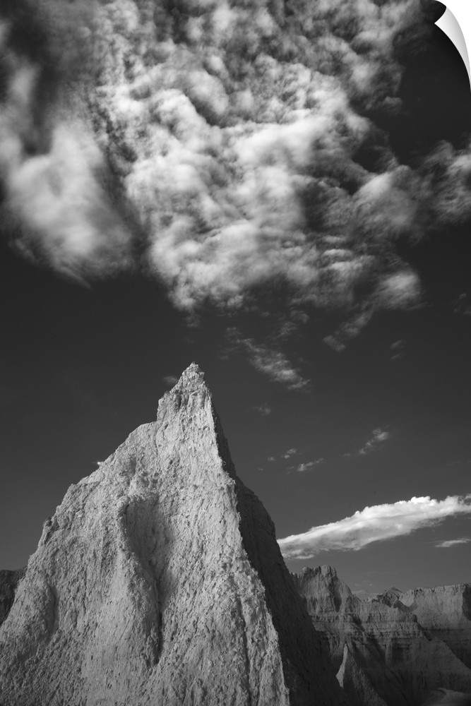 The peak of a mountain almost matching a pointed cloud in the sky, Badlands, South Dakota.
