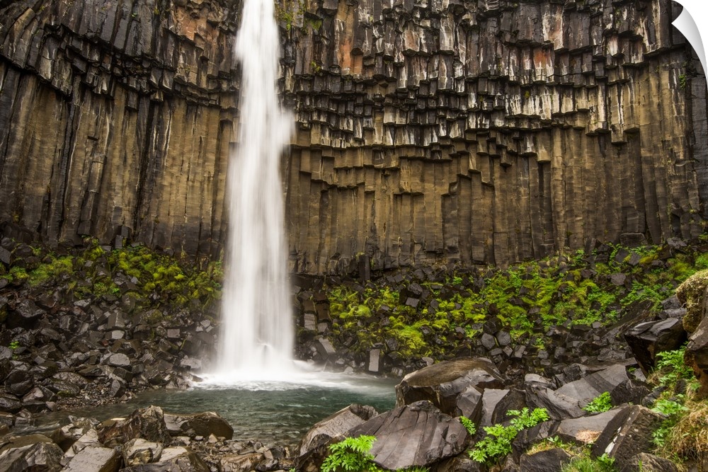 Tall waterfall from a cliff with columnar basalt in Iceland.