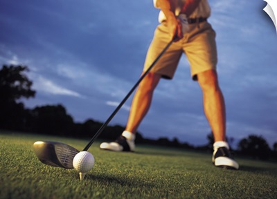 A low angle shot of a golfer preparing to tee off at a golf course