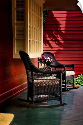 An American front porch with wooden boarding and two whicker rocking chairs