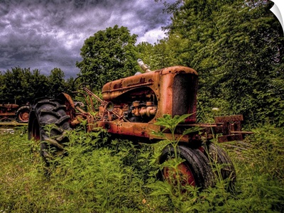 An old red 1950's tractor left to decay in a field