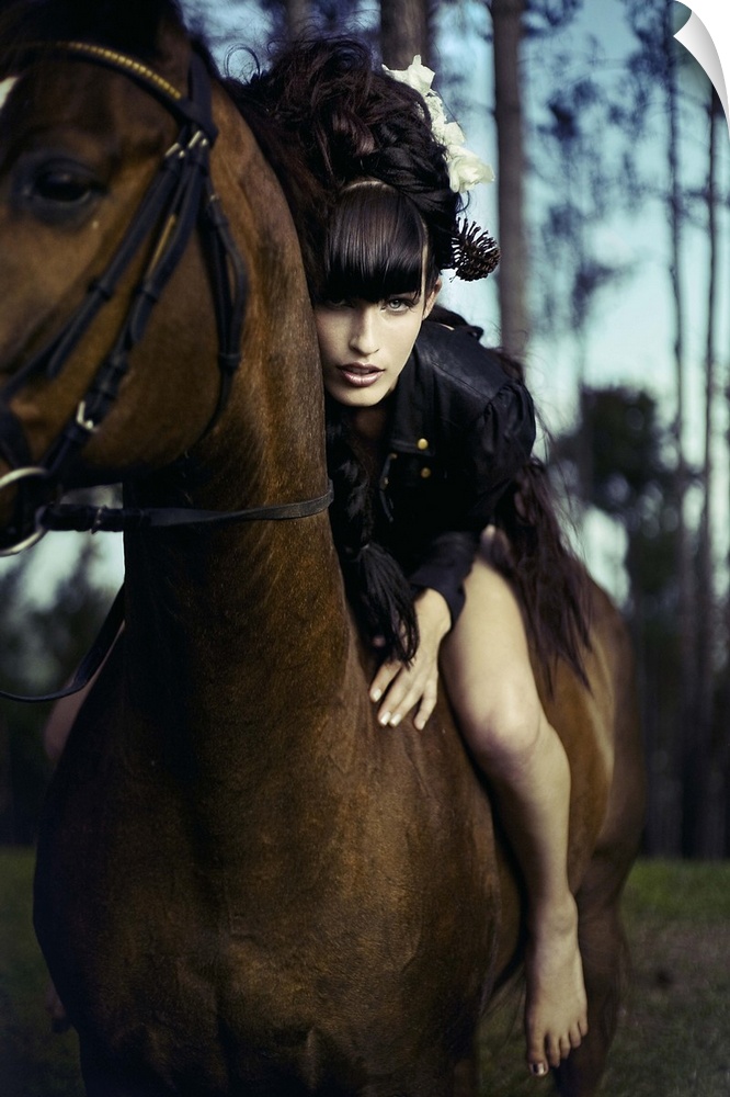 Young woman with black hair sitting bare back on horse leaning forward towards the camera