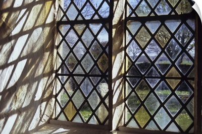 Detail of stone-framed church window with diamond-leaded panes