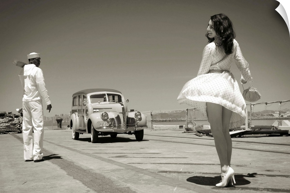 A model wearing a short white dress near a sailor and vintage car