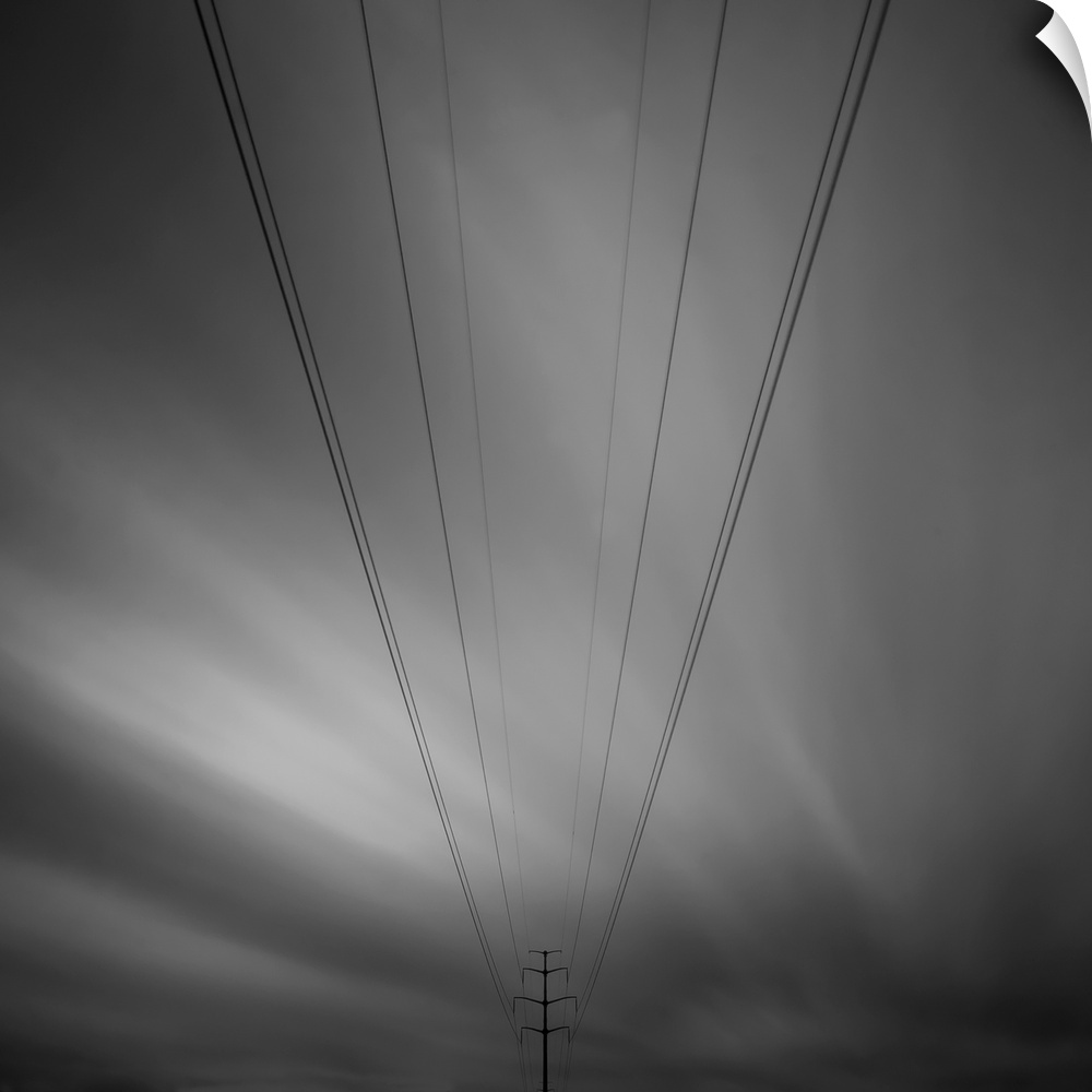 Eight electricity cables leading to a electricity pylon with a strange dramatic black and white sky behind