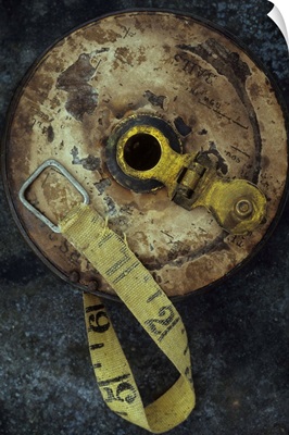 Groundsmans measuring tape in well worn metal case lying on metal sheet