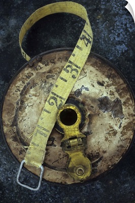 Groundsmans measuring tape in well worn metal case lying on metal sheet II