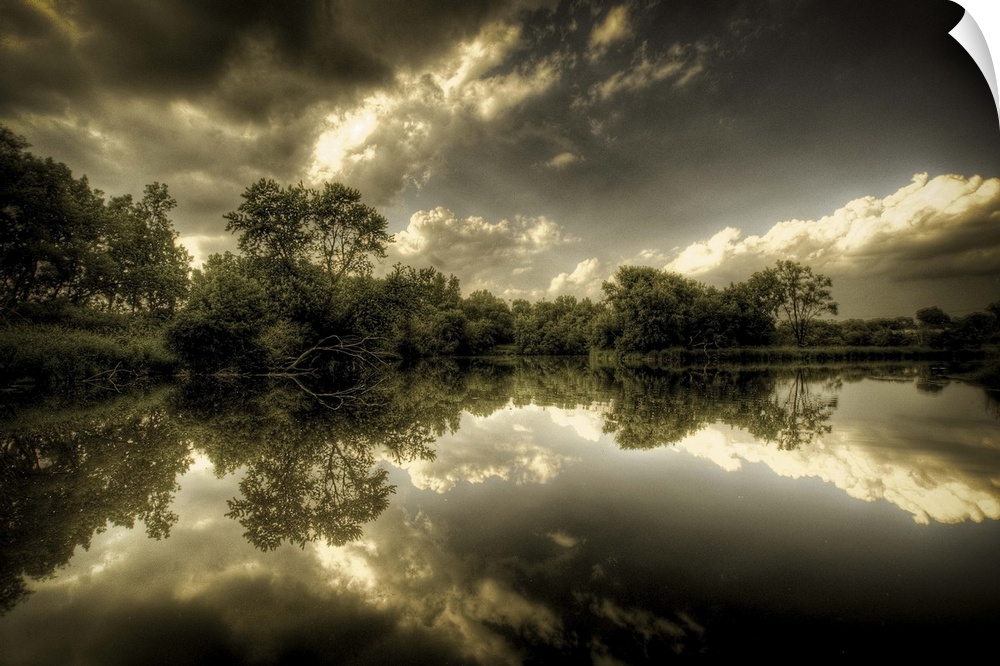 A rural  scene with trees and clouds reflected in the calm waters of a lake