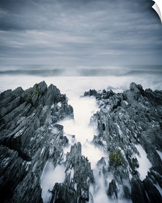 Rough sea with surf and rugged rocks under stormy sky