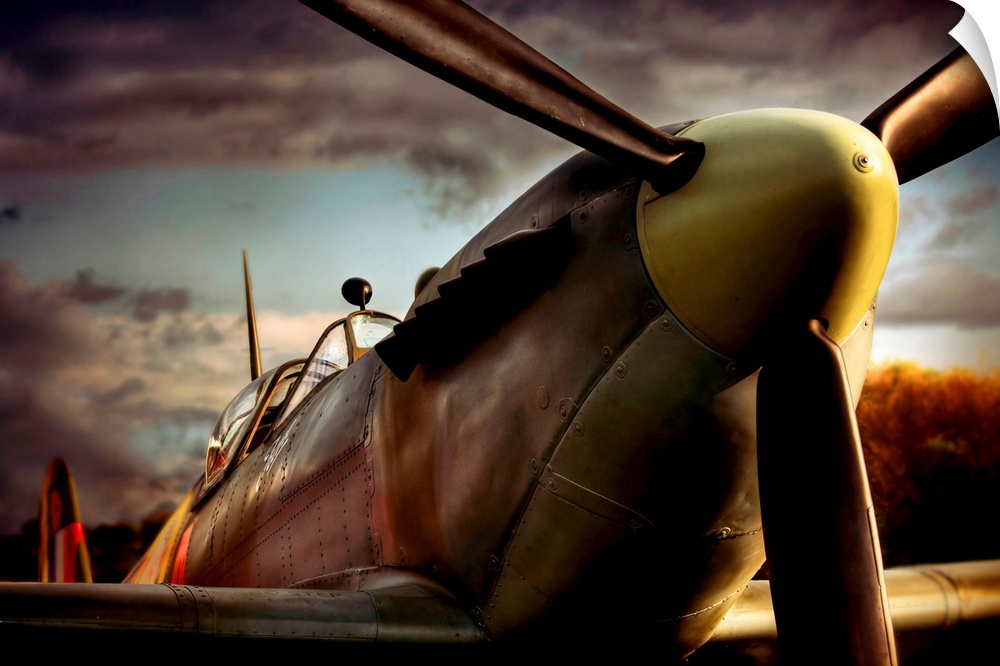 Close up photograph of British Spitfire with dark cloudy sky in the background.  The plane is a single-seat fighter aircra...