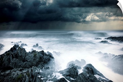 Stormy seascape with rough surf and dark clouds and rocks