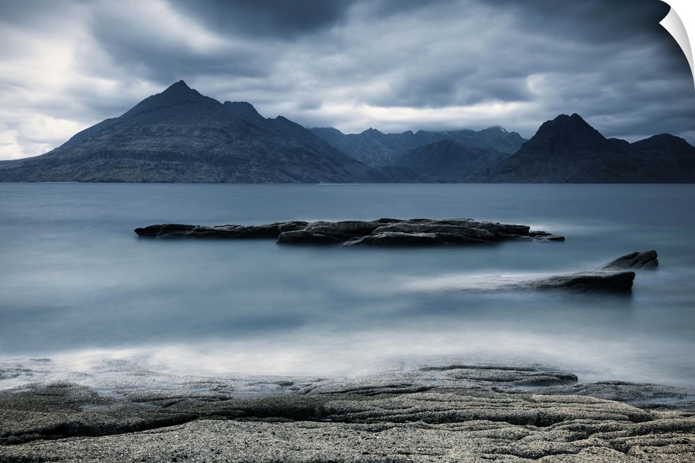Looking across the sea to the Isle of Skye with mountains under a grey sky