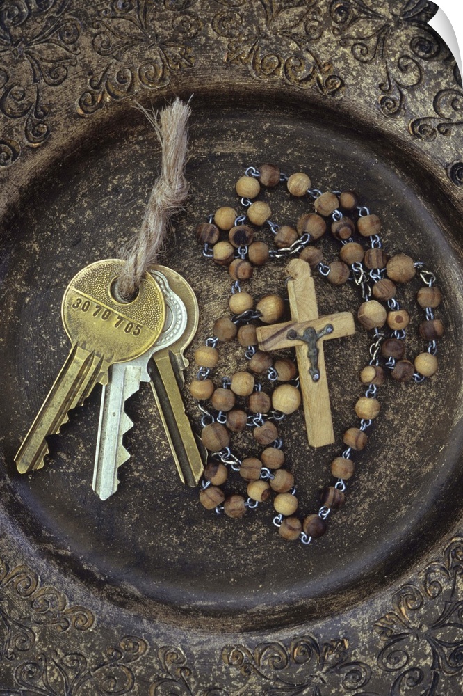 Three brass doorkeys tied with string lying next to rosary with crucifix in brown and gold bowl with intricate pattern