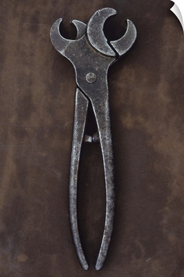 Vintage metal tool with twin heads lying open on metal sheet